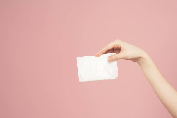 Colocación en el embalaje en manos femeninas sobre un fondo rosa recortado ver higiene aspecto limpio - Foto, Imagen