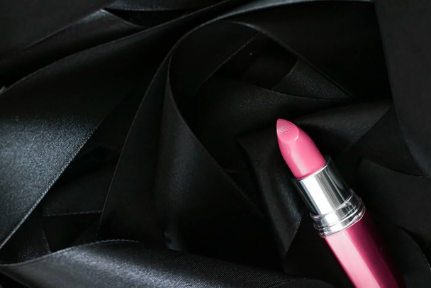 Розовая помада на черном шелковом фоне, роскошный макияж и косметика красоты - Фото, изображение