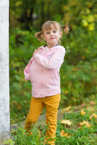.A girl with a broken arm stands near a column in an old park on an autumn walk - Фото, изображение