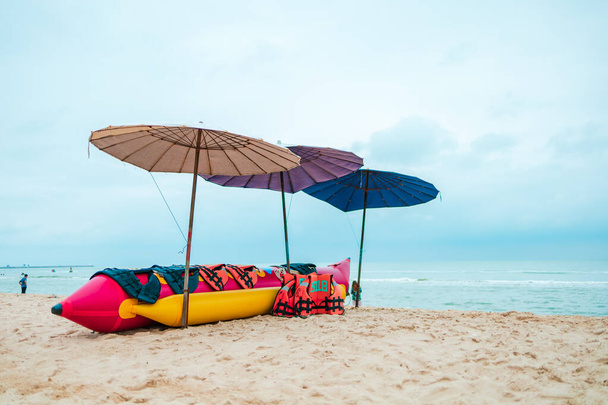 banana boat and life jacket lays on the beach under umbrella. - Foto, Imagem