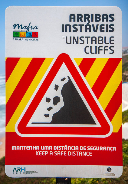 Sign warning for unstable cliffs above the beach area of the town of Ericeira, located north of Lisbon, Portugal - Photo, Image