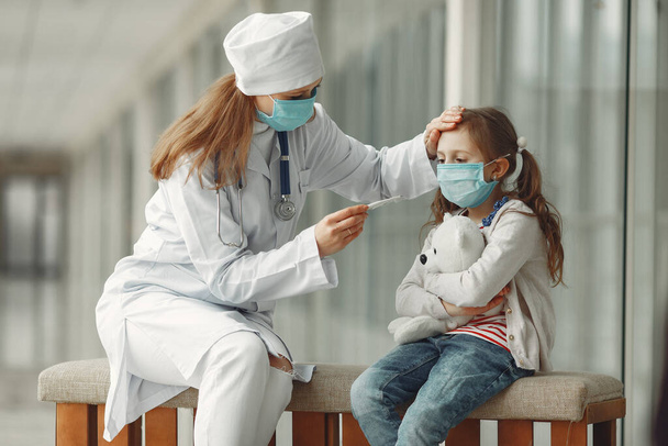 Doctor and a child in protective masks are in hospital - 写真・画像