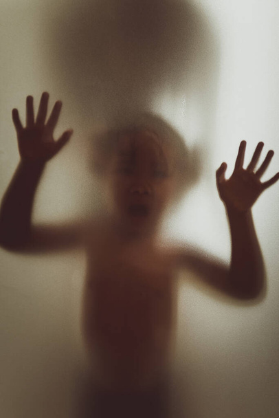 Ghost concept shadow of a child behind the matte glass blurry hand and body soft focus - Photo, Image