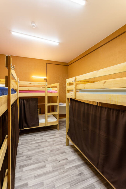 大きなホステルの寮の部屋にカーテン付きの木製の二段ベッド - 写真・画像