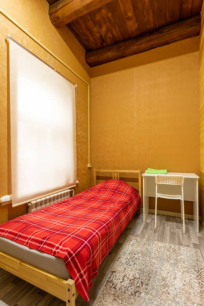Cama de madera con, escritorio y silla en la habitación del albergue - Foto, imagen
