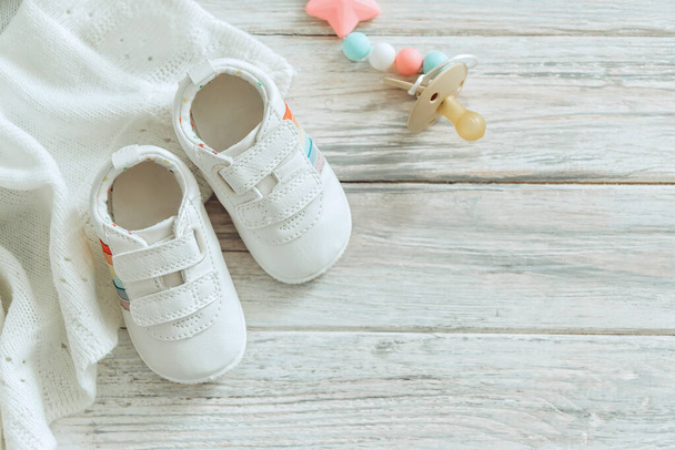 Дитяче біле взуття та тепла ковдра на дерев'яному фоні
. - Фото, зображення