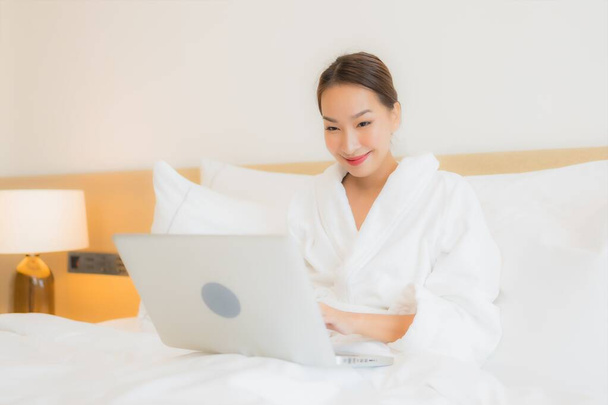Porträt schöne junge asiatische Frau verwenden Computer-Laptop auf Bett im Schlafzimmer Interieur - Foto, Bild