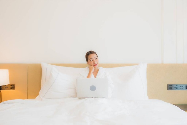 Портрет красивая молодая азиатская женщина использовать компьютер ноутбук на кровати в интерьере спальни - Фото, изображение