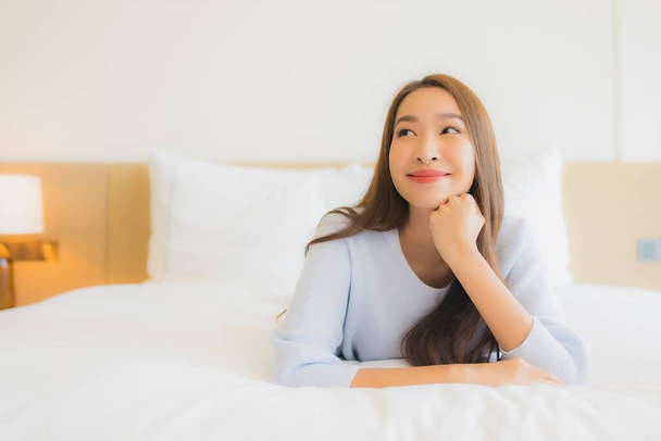 retrato hermosa joven asiática mujer sonrisa relajarse ocio en cama en dormitorio interior - Foto, Imagen
