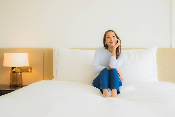 Portré gyönyörű fiatal ázsiai nő mosoly pihenjen szabadidő az ágyon a hálószoba belső - Fotó, kép