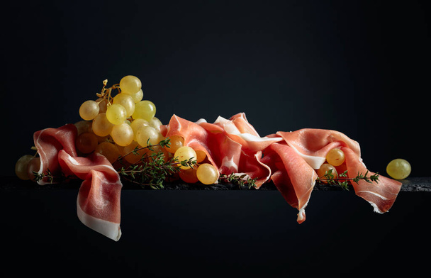 Mediterranean snacks. Grapes with prosciutto and thyme. Copy space. - Фото, изображение