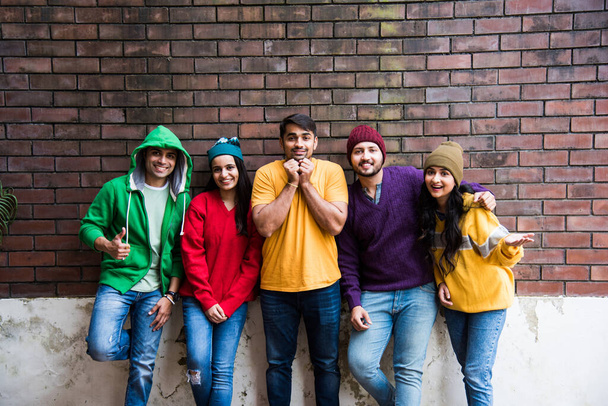Indiana asiático jovens amigos usa colorido e quente lã camisolas e chapéus e apontando - Foto, Imagem