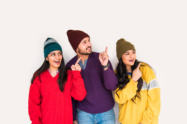 Індійські молоді друзі азіатського походження носять барвисті і теплі вовняні светри і капелюхи і вказують на - Фото, зображення