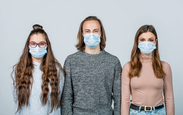 Молодые люди носят маску для предотвращения вспышки коронного вируса. Здоровье, карантин и пандемия - группа людей в защитных медицинских масках для защиты от вируса - Фото, изображение