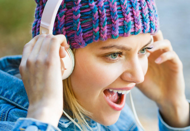 Cheerful girl rejoicing listening music in headphones smiling. Girl listens to music in headphones. Listening to music.Autumn melody concept. Young woman with big headphones - Photo, Image