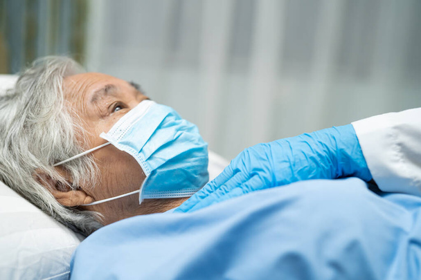 Medico che utilizza lo stetoscopio per controllare la paziente anziana anziana o anziana asiatica che indossa una maschera facciale in ospedale per proteggere l'infezione Covid-19 Coronavirus. - Foto, immagini