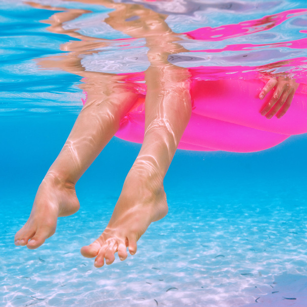 Donna che si rilassa sul materasso gonfiabile, vista da sott'acqua
 - Foto, immagini