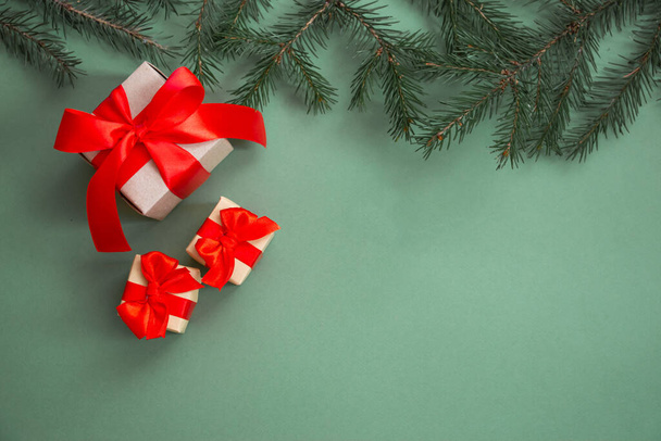 Рождественская композиция Подарки с красным луком, елки ветви, новогодние украшения на зеленом фоне. Плоская лежала, вид сверху, копировальное пространство. Зимняя праздничная концепция. - Фото, изображение
