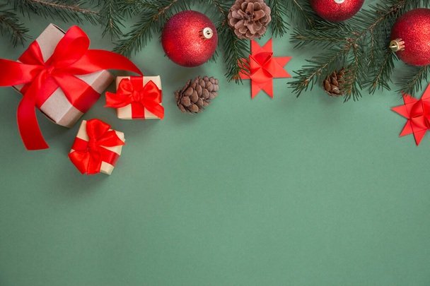 Christmas composition. Gifts with a red bow, spruce branch, New Year's decorations on a green background. Flat lay, top view, copy space. Winter festive concept. - Photo, image