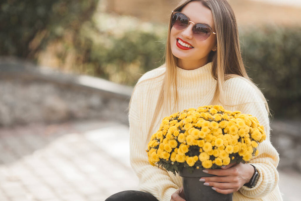 Schöne Dame auf herbstlichem Hintergrund mit gelben Blumen - Foto, Bild