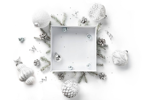 Merry Christmas card made of gift box, white and silver decorations, fir branches, sparkles and confetti on white background. Xmas and New Year holiday, bokeh, light. Flat lay, top view - Photo, Image
