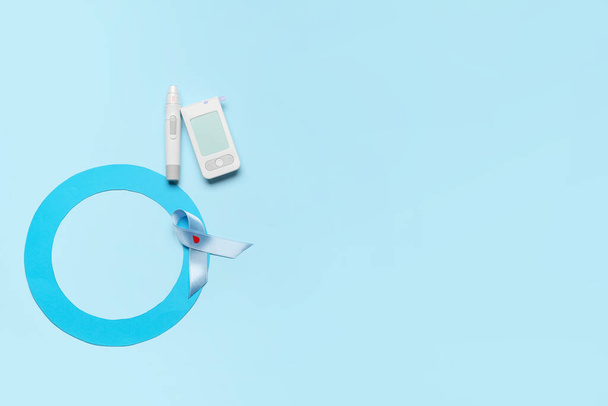 Glucometer with lancet pen, blue ring and awareness ribbon on color background. Diabetes concept - Fotografie, Obrázek