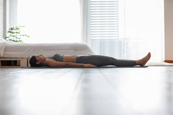 Calm of Asian indian woman practice yoga Dead Body or Savasana pose with meditation smile at home Feeling so comfortable and relax,Healthcare Concept - Foto, afbeelding