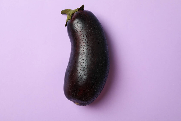 Fresh raw eggplant with water drops on violet background - Foto, Imagem