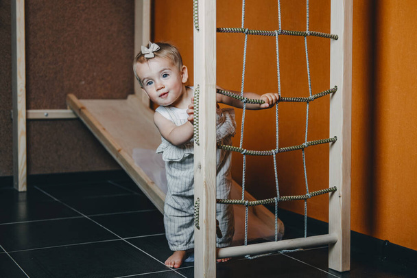 Active games for Baby indoors activities. Toddler girl play on home Wooden indoor playsets. Play Gym, Home and School Indoor Wooden Playground Equipment for kids Children with Climbing Net, Slide - Photo, Image