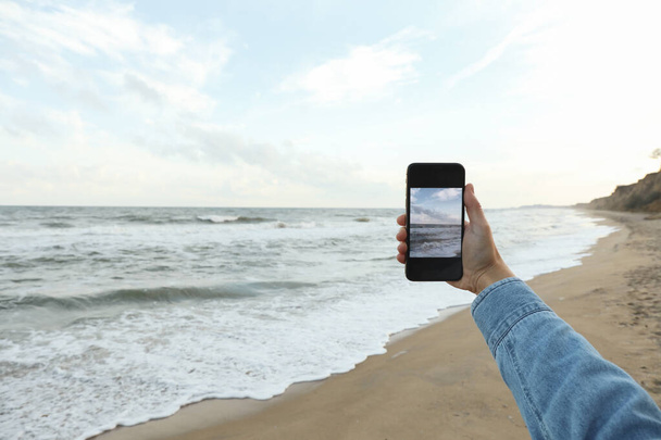 女性手携帯電話ともに作る自撮り上の海 - 写真・画像