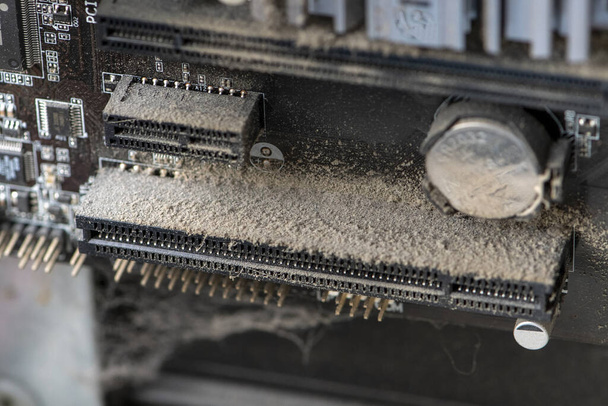 Dust and dirt on the computer's motherboard. Concept: old hardware, risk of computer fire, slowing down the hard disk, prevention and diagnostics, repair and replacement. - Foto, immagini