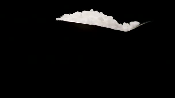 Sól morska spadająca z łyżki w zwolnionym tempie izolowana na czarnym tle - Materiał filmowy, wideo
