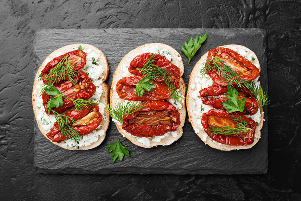 Leipäviipaleet ricotta-juustolla ja aurinkokuivatuilla tomaateilla oliiviöljyssä. - Valokuva, kuva