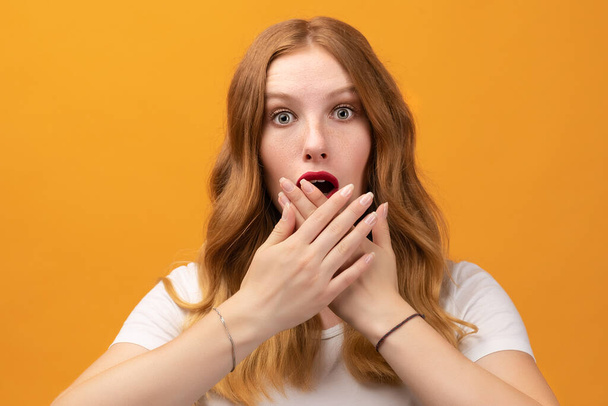 I'm afraid. Fright, phobia, panic attack, horror. Portrait of the scared girl with wavy redhead, wearing white t-shirt, isolated on yellow background - Photo, Image