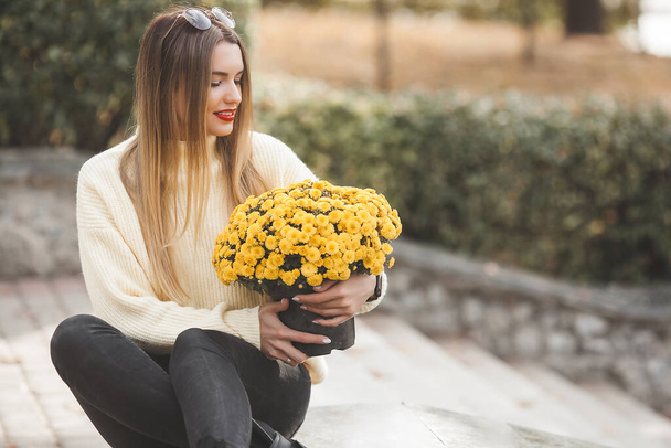 Hermosa dama en el fondo de otoño con flores amarillas - Foto, Imagen