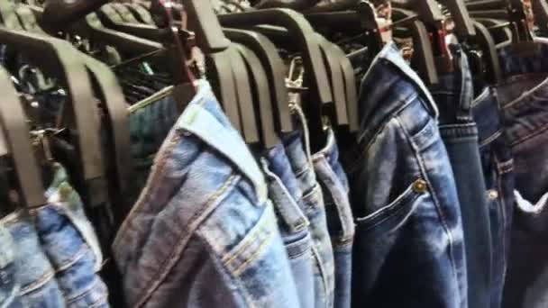  Kamerabewegung entlang einer Reihe von riesigen blauen Jeans auf Kleiderbügeln. Das Konzept des Shoppings, schwarzer Freitag  - Filmmaterial, Video