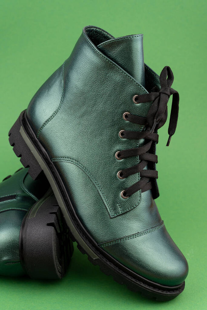 Green leather shoes. Winter and autumn off-season boots. Stylish boot isolated on background. Close-up. Laces, tractor sole, comfortable last. Casual style. Copy space. Pearlescent fashionable color. - 写真・画像