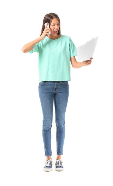 Stressed young woman talking by mobile phone on white background - Φωτογραφία, εικόνα