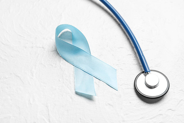 Blue ribbon and stethoscope on white background. Prostate cancer awareness concept - Zdjęcie, obraz