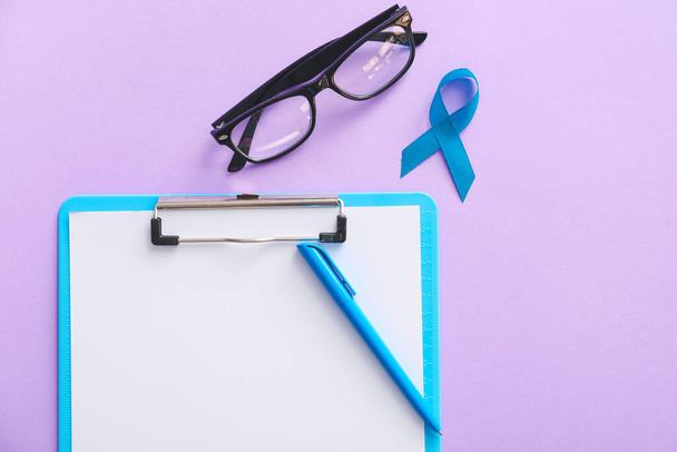 Ruban bleu, lunettes et presse-papiers sur fond de couleur. Concept de sensibilisation au cancer de la prostate - Photo, image