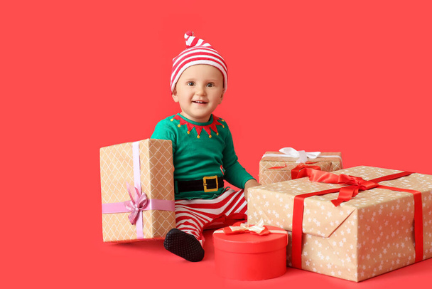 Cute little baby w stroju elfa i z prezentów na tle kolorów - Zdjęcie, obraz