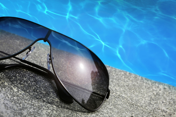 γυαλιά ηλίου, δίπλα σε μια πισίνα - Φωτογραφία, εικόνα