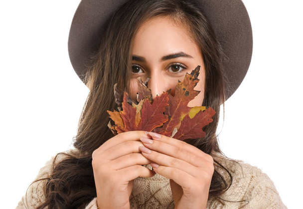 Stylish young woman with autumn leaves on white background - Foto, afbeelding