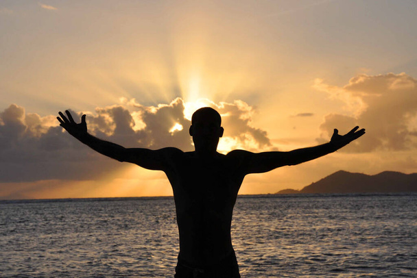 Силует людини з руками хрест на пляжі на заході сонця
 - Фото, зображення
