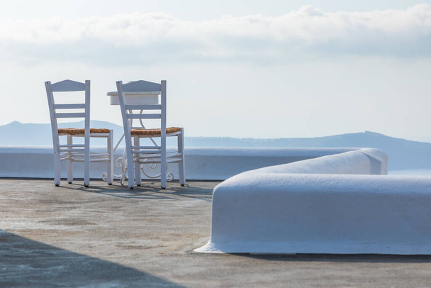 Sedie bianche e tavoli sulla terrazza con vista sulla caldera, Fira, Isola di Santorini, Grecia. - Foto, immagini