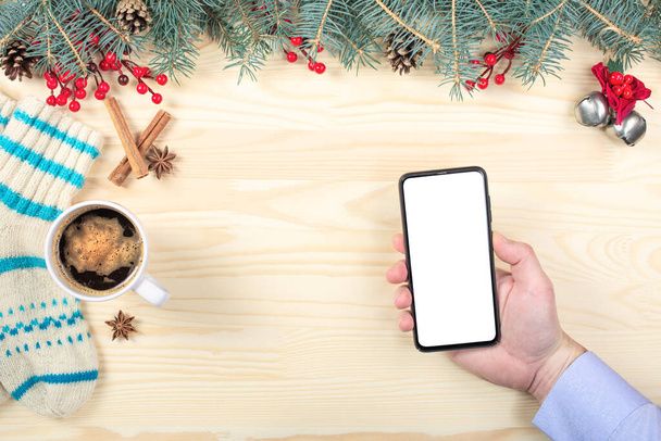 mobile phone mockup on Christmas background. Hand holding blank screen mobile cell phone. mockup christmas concept. close up top view - Foto, imagen