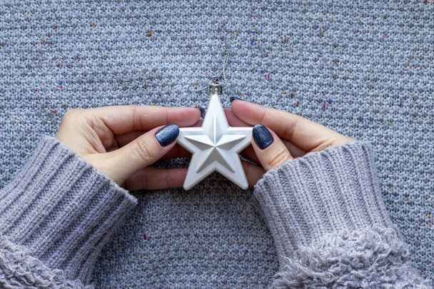 As mãos femininas no suéter tricotado com estrela de árvore de Natal branca e com a bela manicura - azul cinza escuro brilharam pregos no contexto tricotado - Foto, Imagem