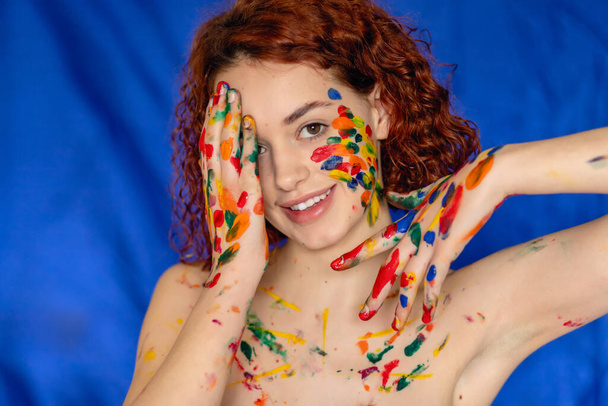 Close-up portrait of red curly haired woman Young cheerful soiled in paint. Portrait of a girl with a creative pattern on her face. Concept photography for art or women's blog - Photo, Image