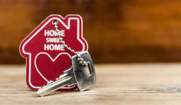 Ключи от дома с брелоком в форме дома на деревянном фоне - Фото, изображение