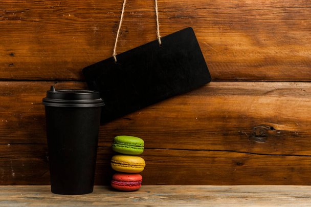 macaroons ja kertakäyttöinen kahvikuppi puinen maalaismainen pöytä - Valokuva, kuva